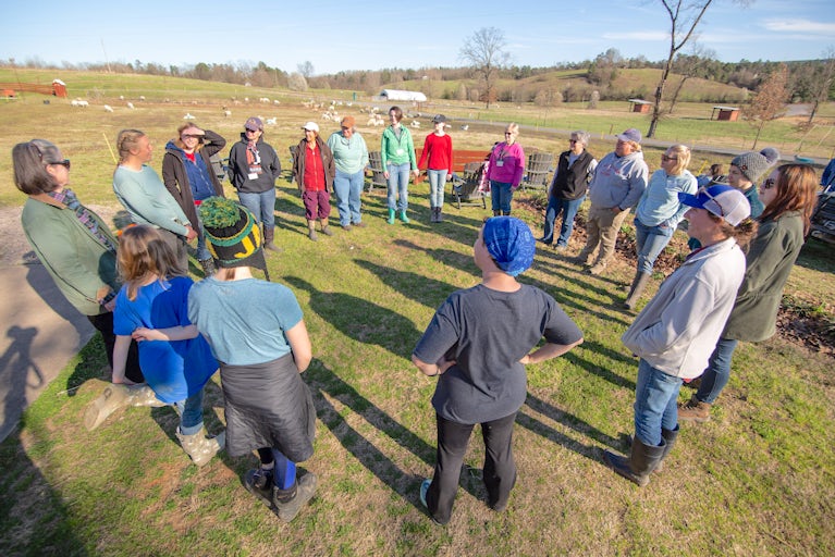 Group of volunteers standing in a circle in a field.