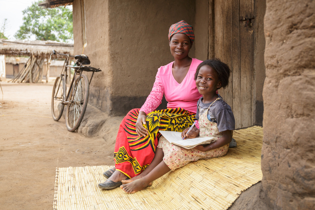 Glyceria helps her daughter, Julita, do her homework.