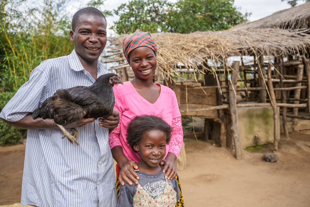 Chinzimu holds one of the family’s chickens alongside his wife, Glyceria, and their daughter, Julita.