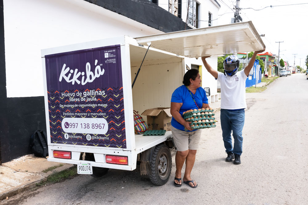 A woman unloads trays of eggs from a 'Kikiba' vehicle.
