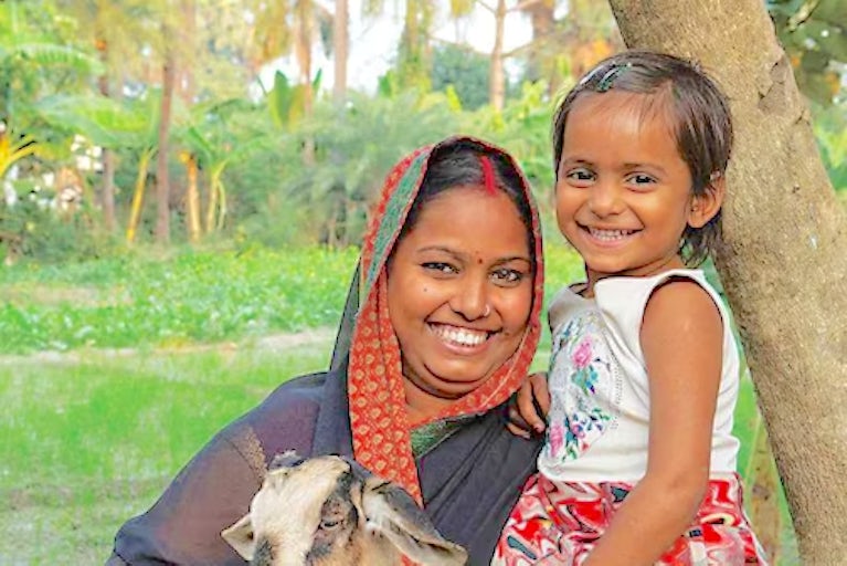 Mother and child holding a goat.
