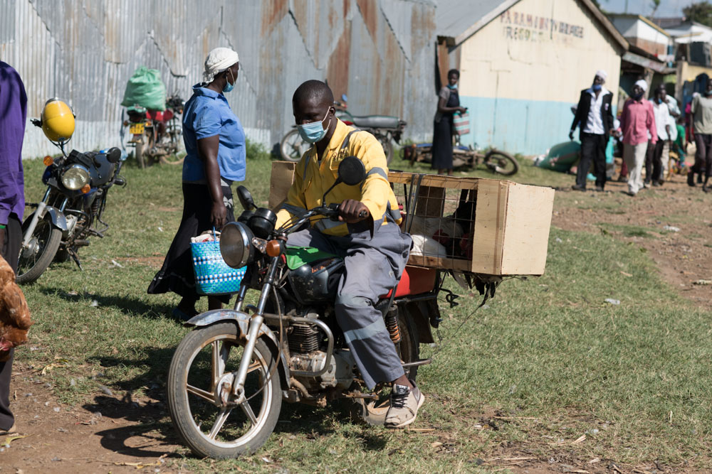 A man drives a motorbike through a crowded area in Kenya.