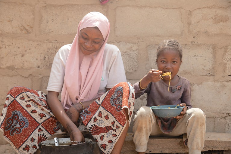 Woman cooking while little girl eats