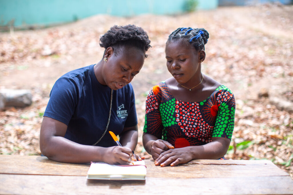 Two women sit at a wooden table during a financial training session.