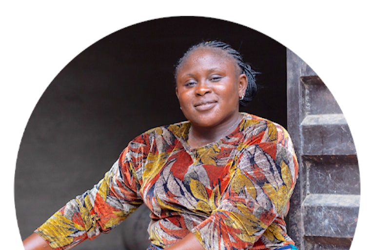 Woman in Nigeria poses while holding a bowl of rice.
