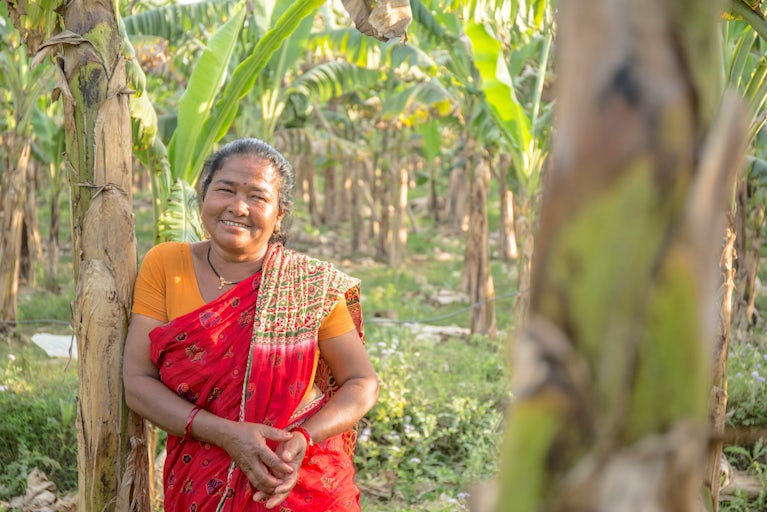 Woman leaning against a tree in the jungle and smiling.