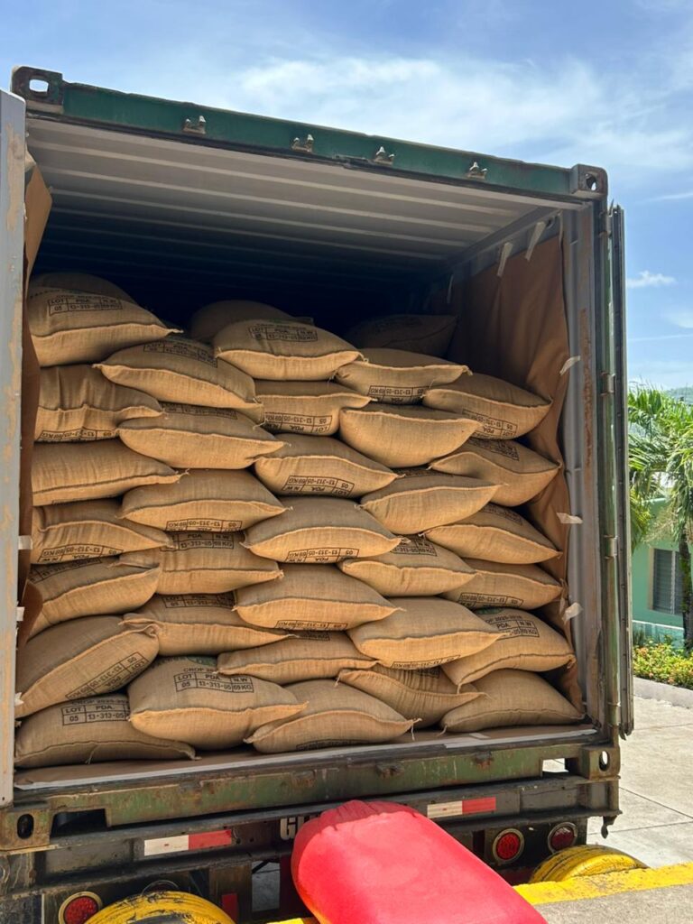 Burlap sacks of coffee fill an open shipping container.