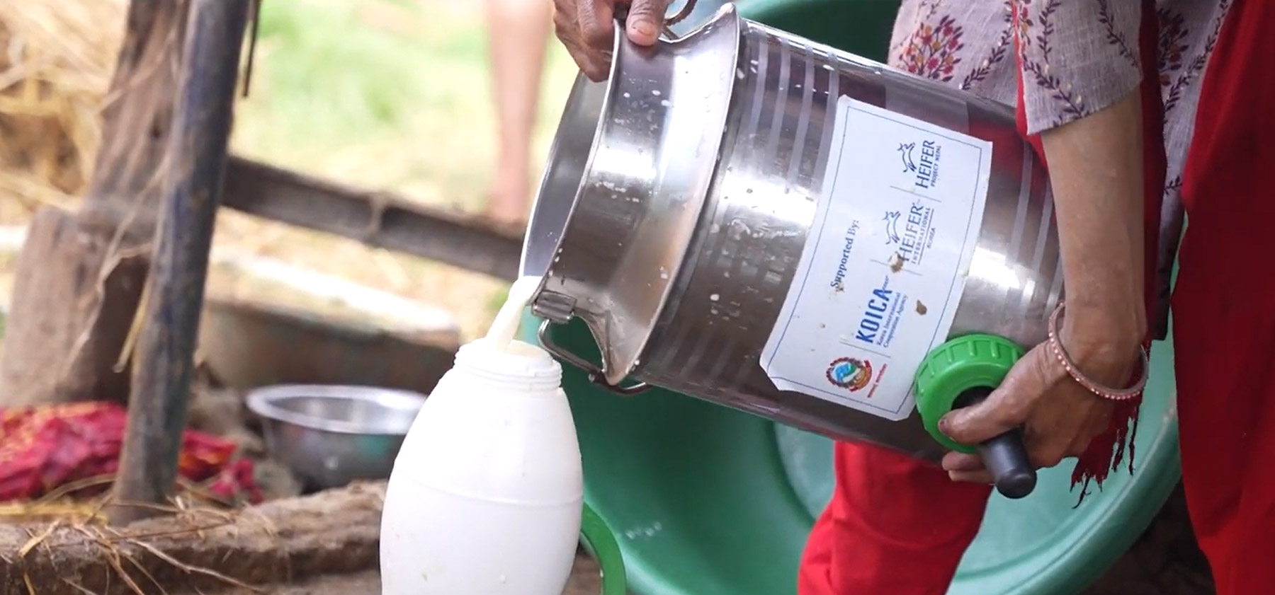 Close-up of hands pouring milk from a container into a bottle.