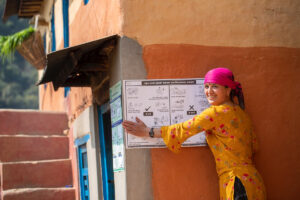 A woman attaches a sign to a brick wall.