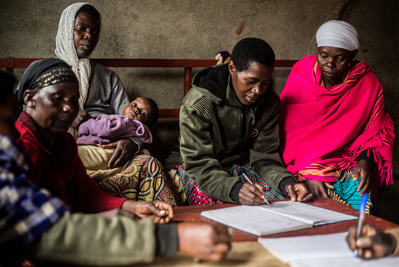 A group of women sit together and consult paperwork in Rwanda.