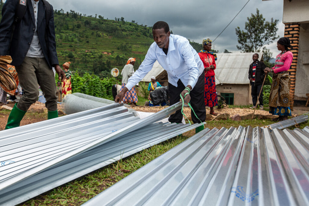 A man arranges metal roofing sheets outdoors.