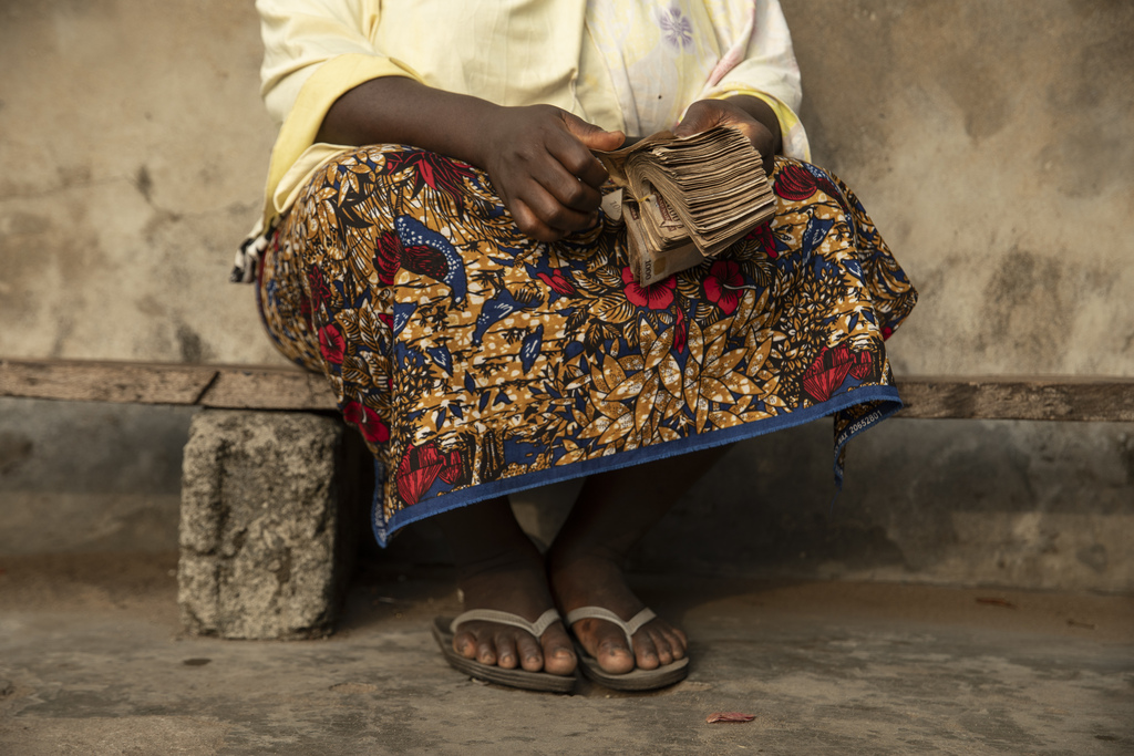 A person counts a stack of cash while seated.