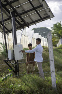 Minh Savoeun, 57, (right) talks to Run Rothna, 15, about the solar panels used to power water irrigation in Prey Vihear commune, Cambodia on December 14, 2024.
