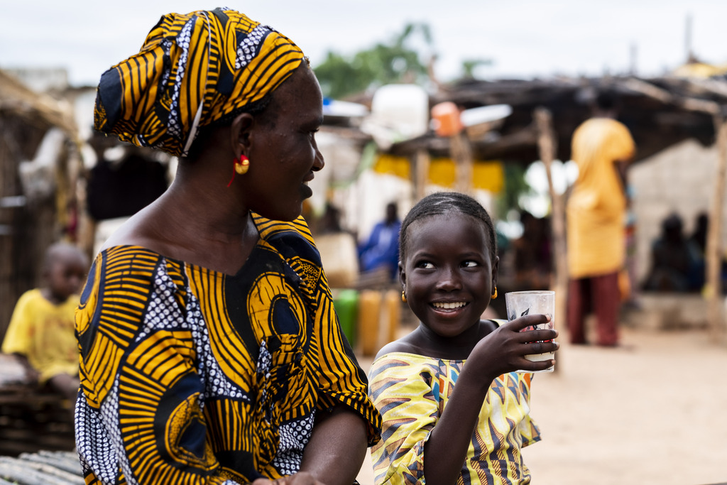 Khardiata Alassane Ba drinks fresh milk as she looks at her mother.