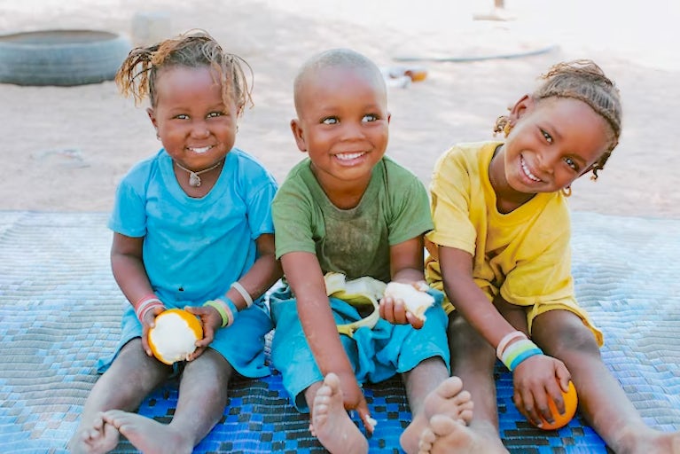 Three children sitting next to each other smiling.