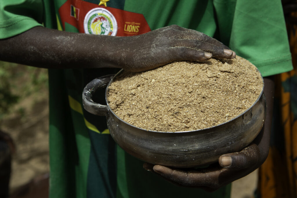A person holds a bowl of livestock feed in Senegal.