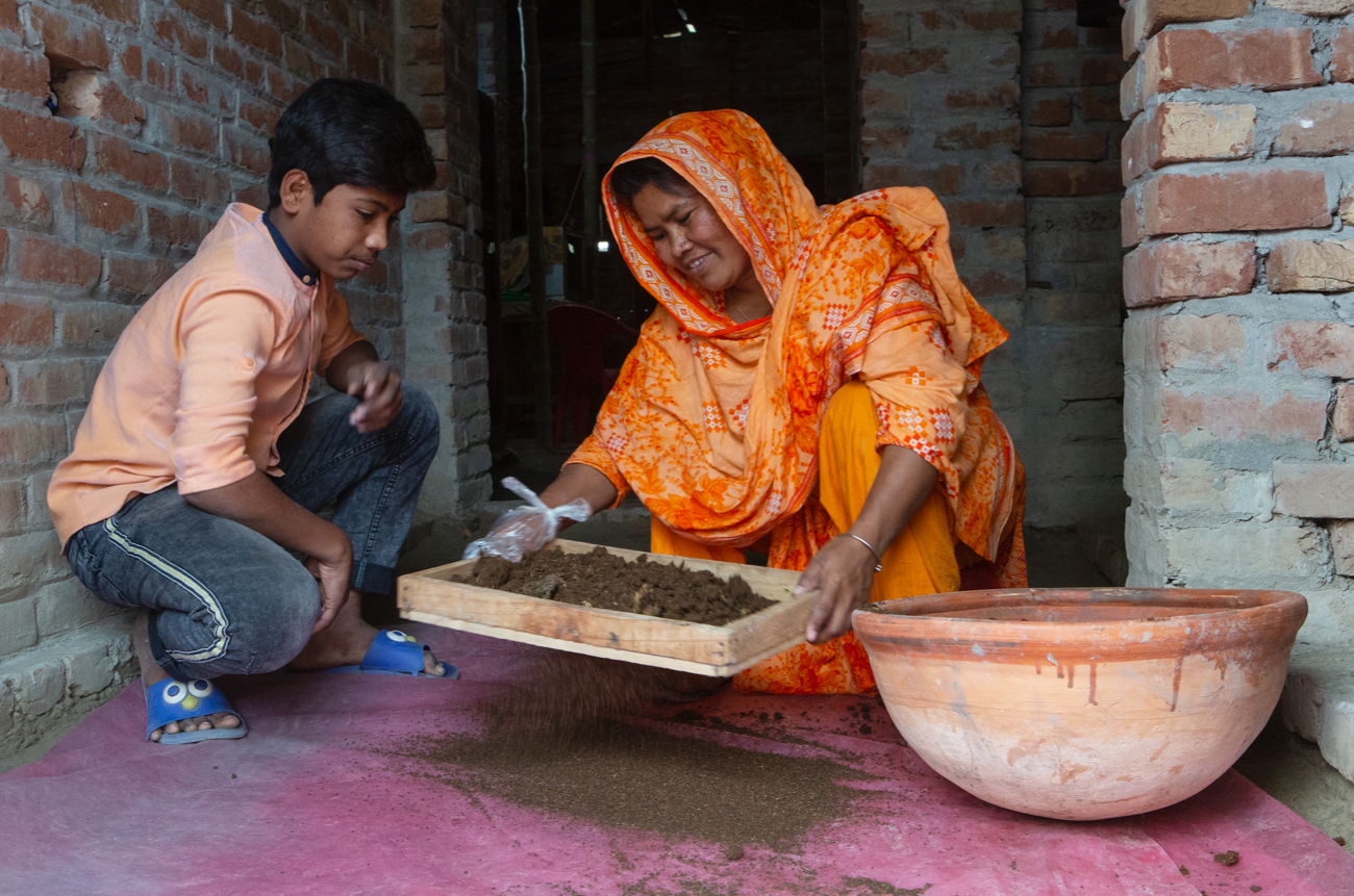 A Bangladeshi woman and her son tend to a basket of compost.
