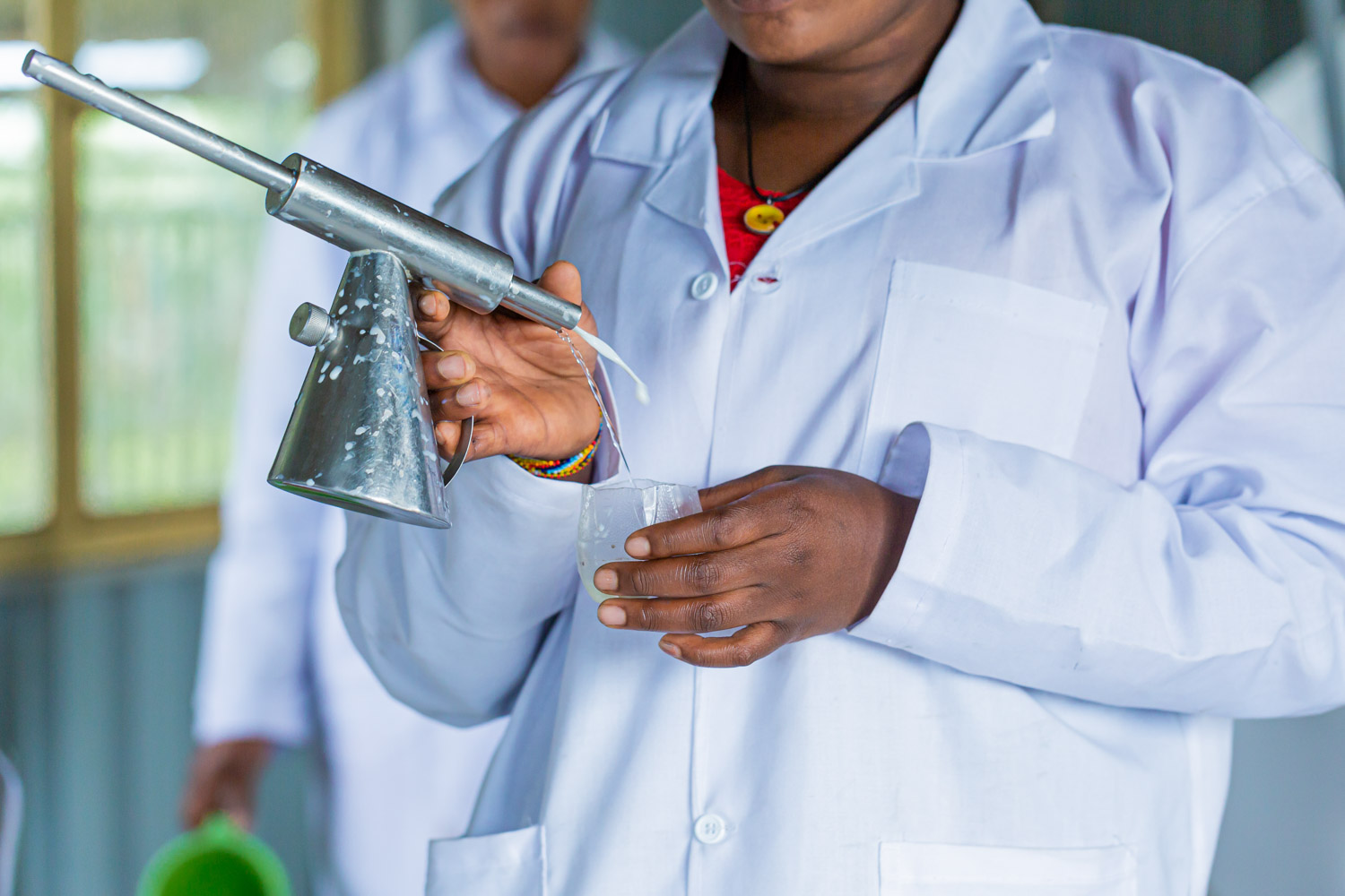 A close-up of a dairy worker's hands holding a milk testing instrument.