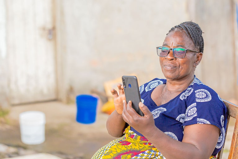 Woman in patterned dress uses a smartphone.