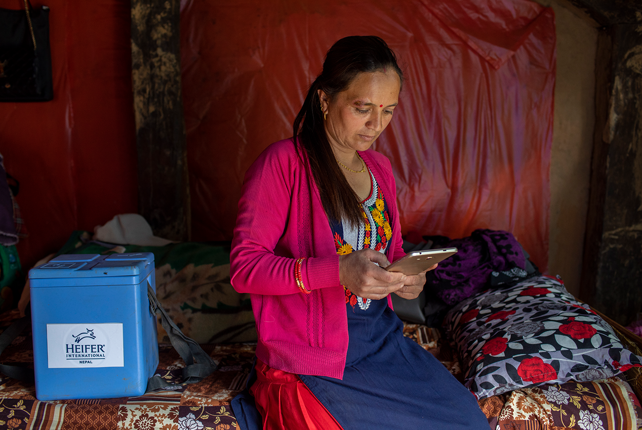 A woman sits on her bed and looks at a tablet.