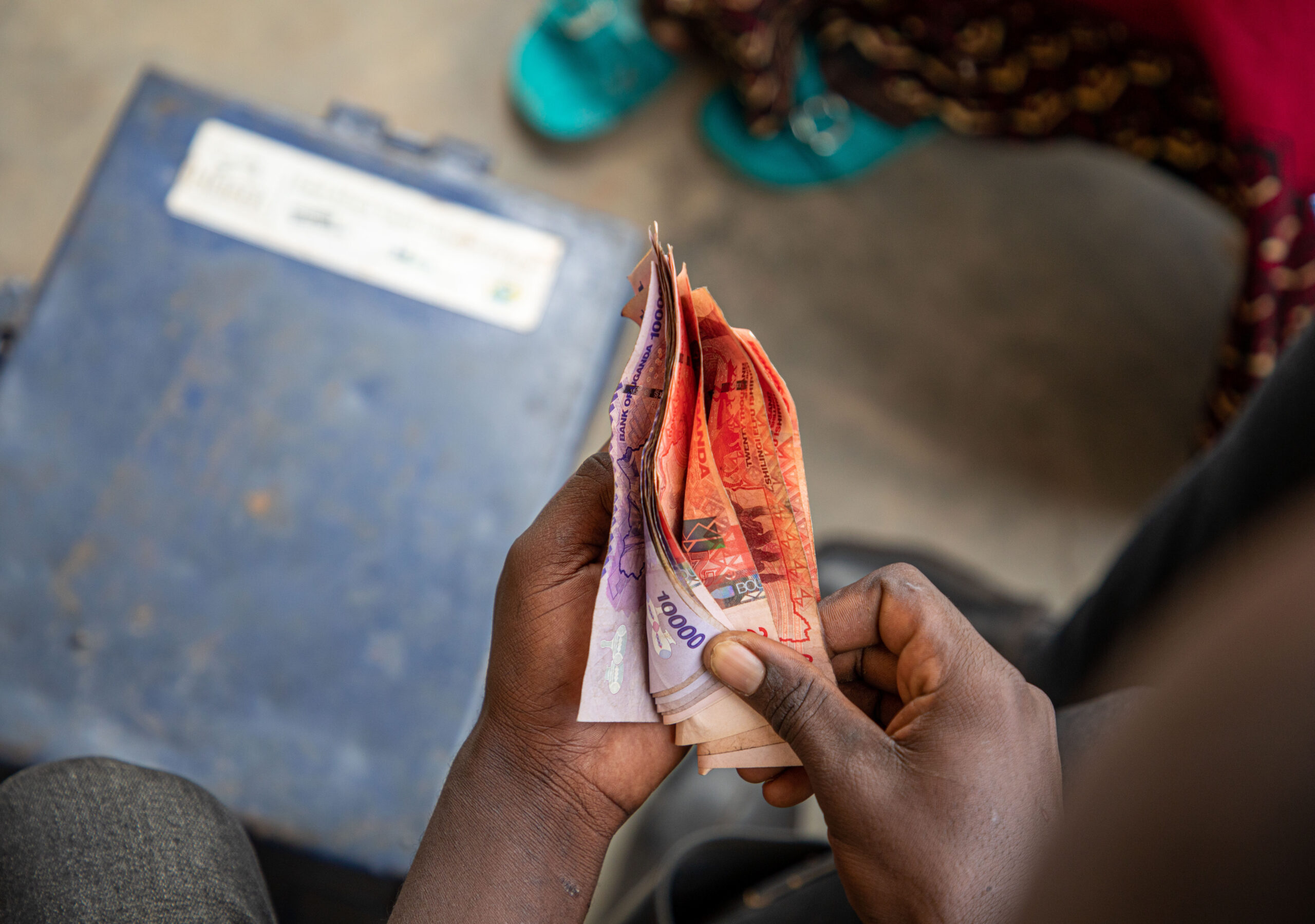 Hands count a stack of bills in Uganda.