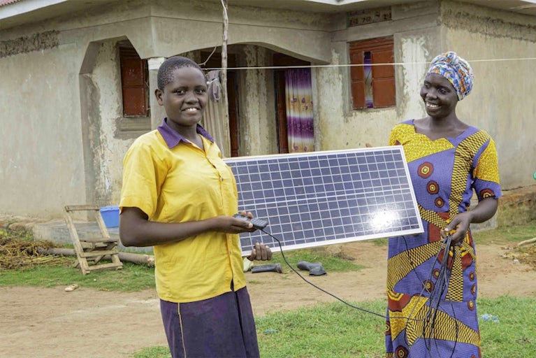 Acico Flavia, 15, and Sarah Akello, 31, hold a solar panel donated from Heifer International in Aduudyek village, Uganda.