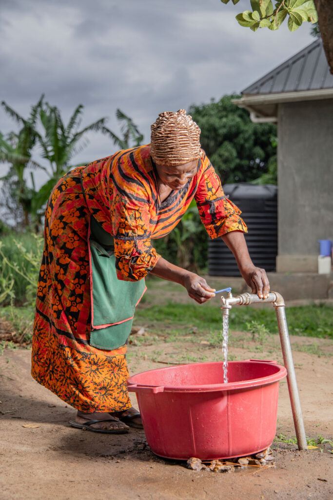 A woman fills a basin with water from a tap.