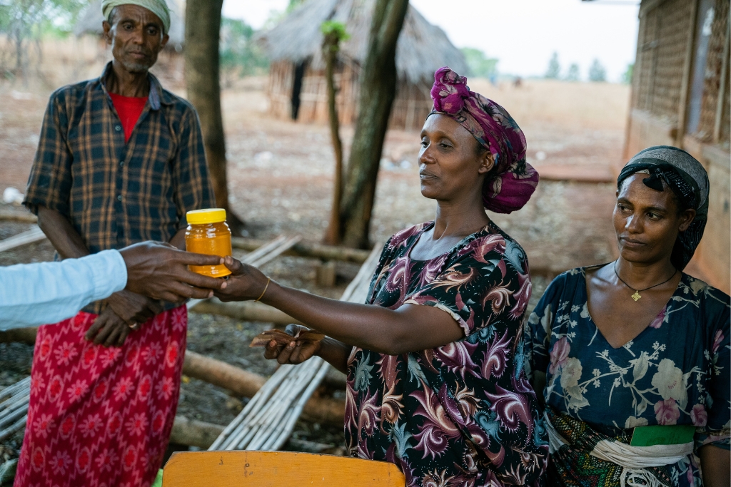 Workeye Endris (29) and Bezuye Yalew (30) selling their honey to a customer at the honey storage and shop of the Common Interest Group (CIG) in Asosa, Abrahamo woreda.