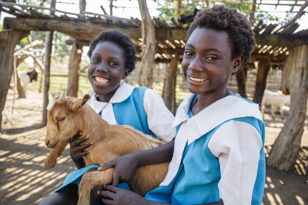 Prudence Kaumbo, 13, (left) and her cousin Emmy Nswana, 13, with one of the family's goats.