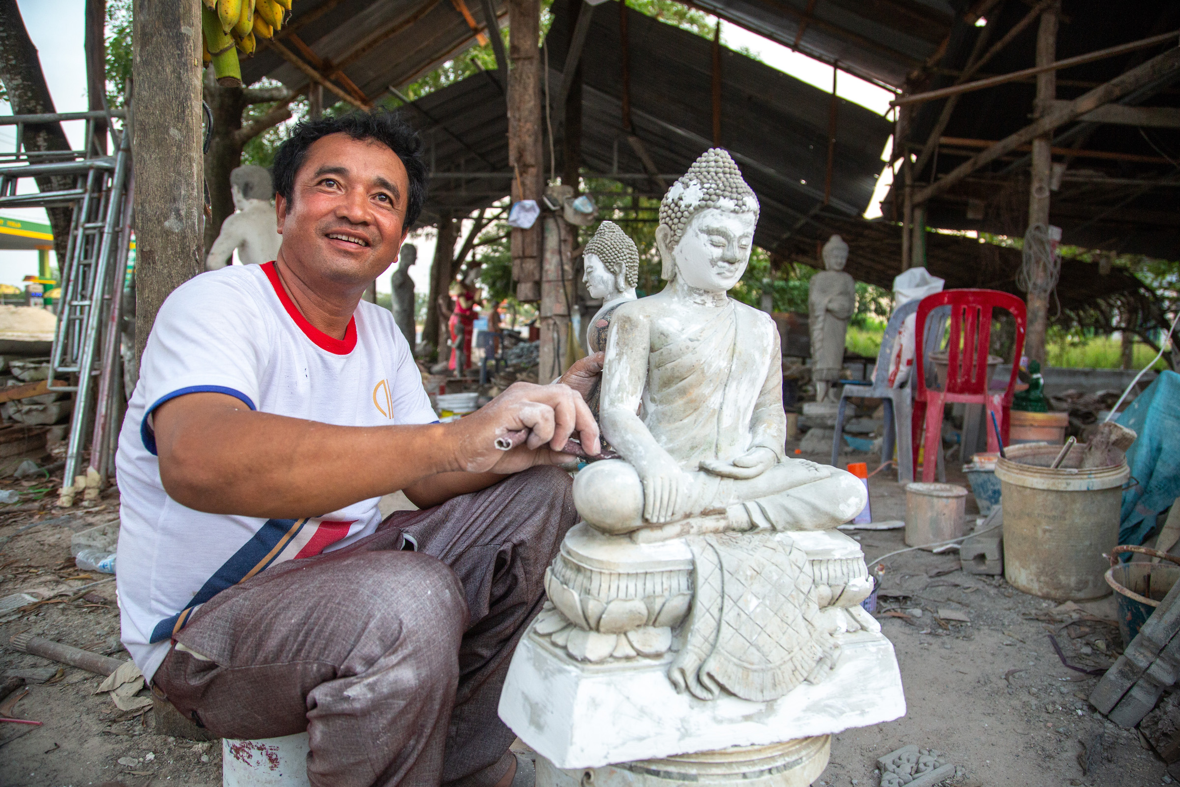 Artisan Em Sameoun crafts spirit houses and Buddhist statuary at his roadside workshop.