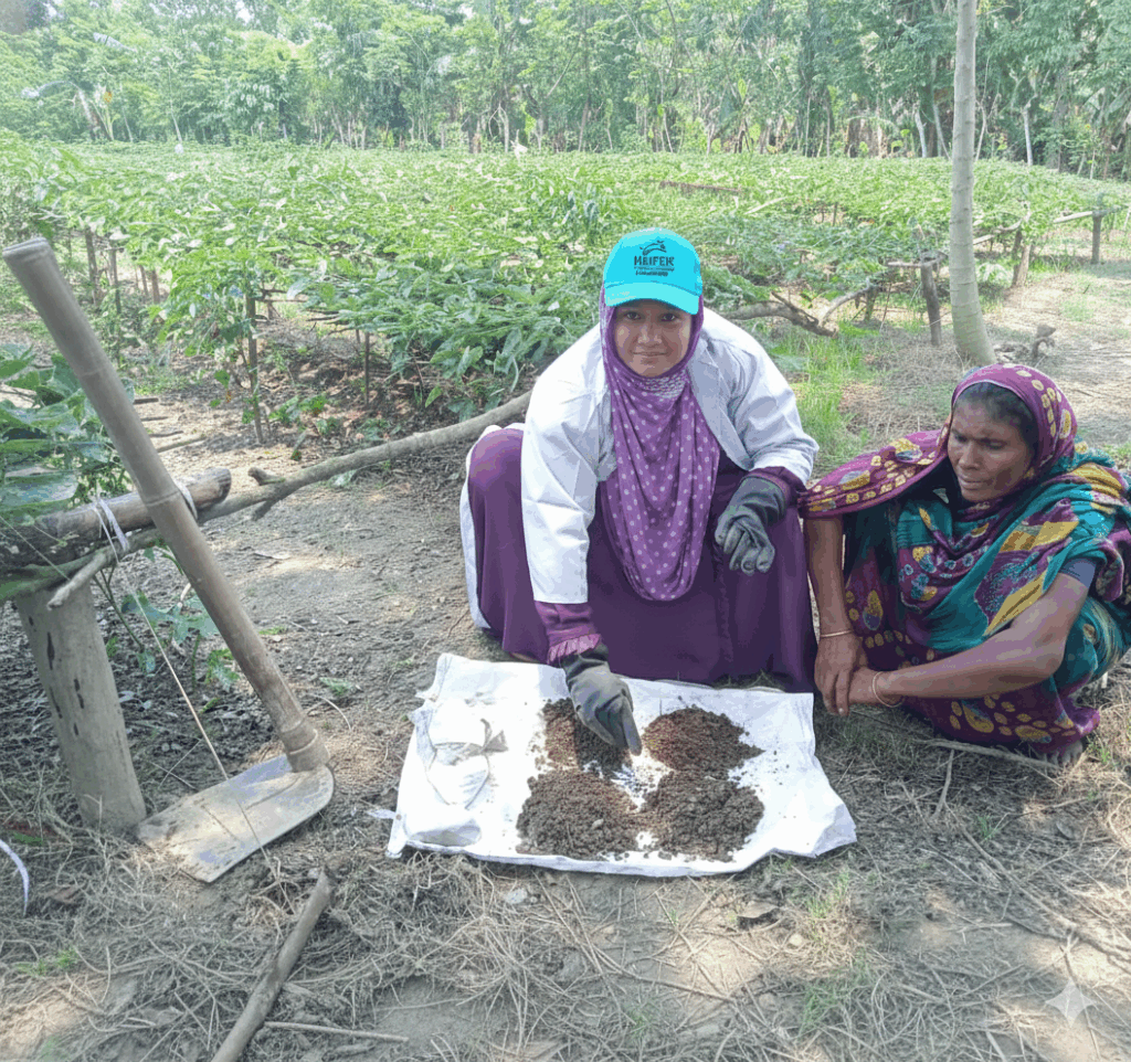 Two women crouch beside a soil sample.