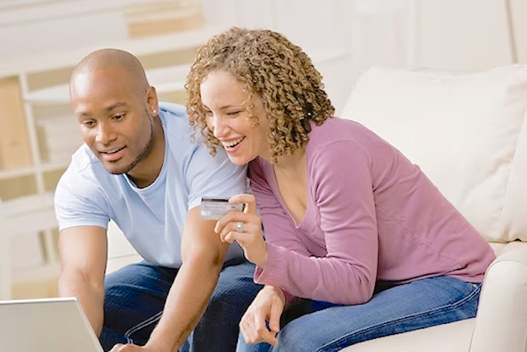 A man and a woman shop online on a laptop
