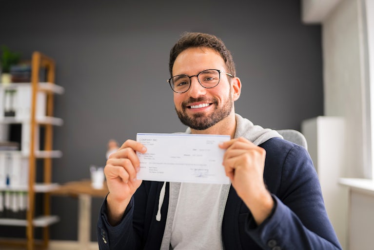 A man holds up his paycheck.