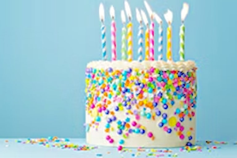 Birthday cake on table with blue background.