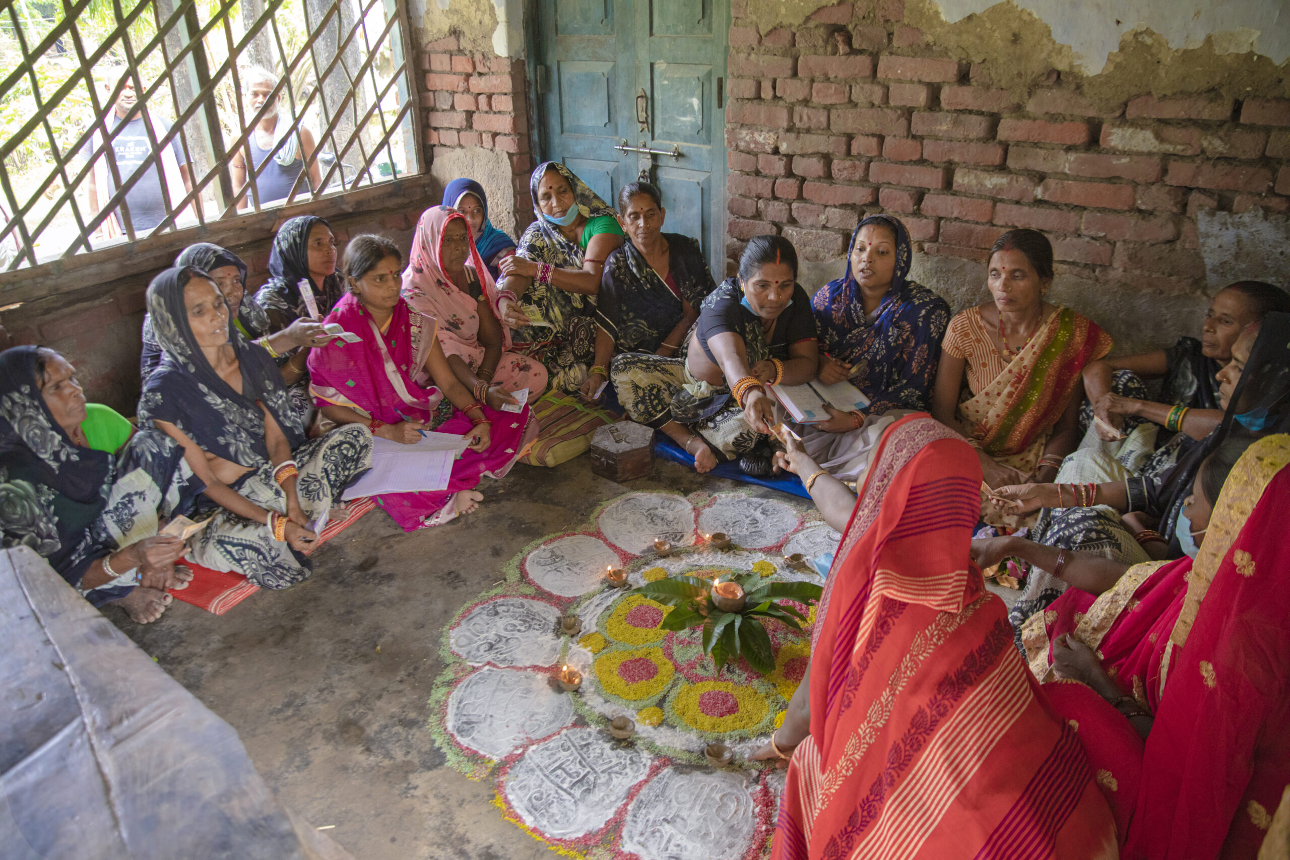 Group of women dressed in cultural attire and sitting in a circle.