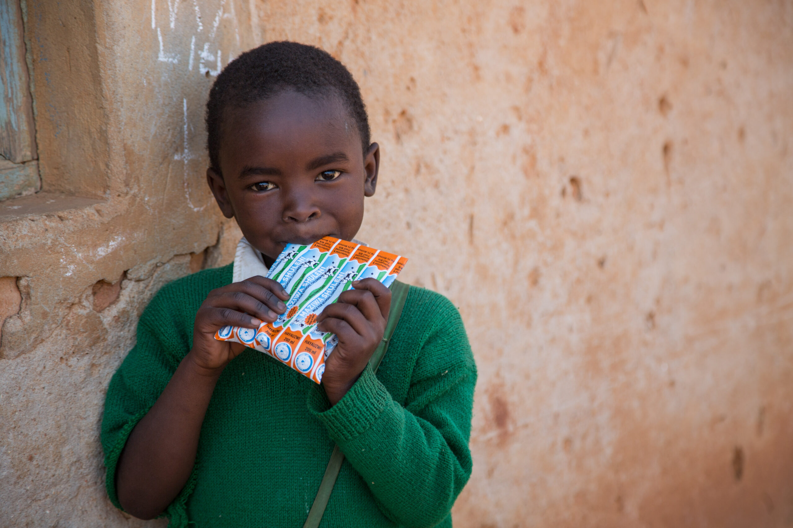 Happy kids at the Itunduma elementary school hold and suck on milk packets.