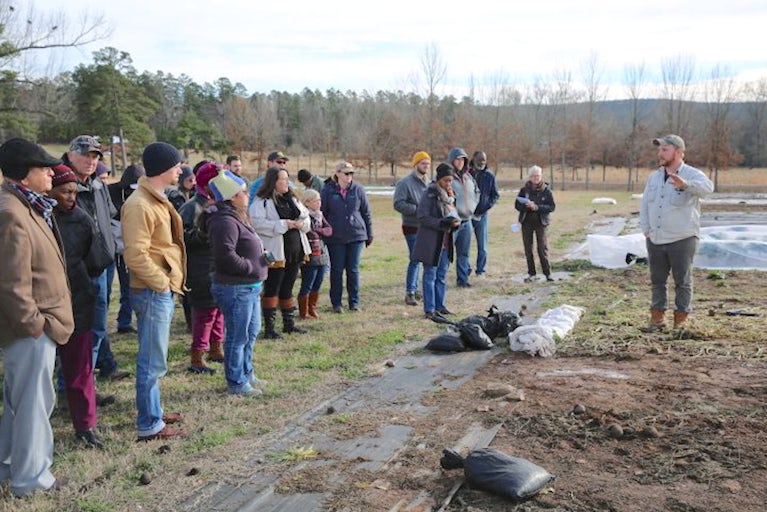 Farmer training a group of people in an open field.