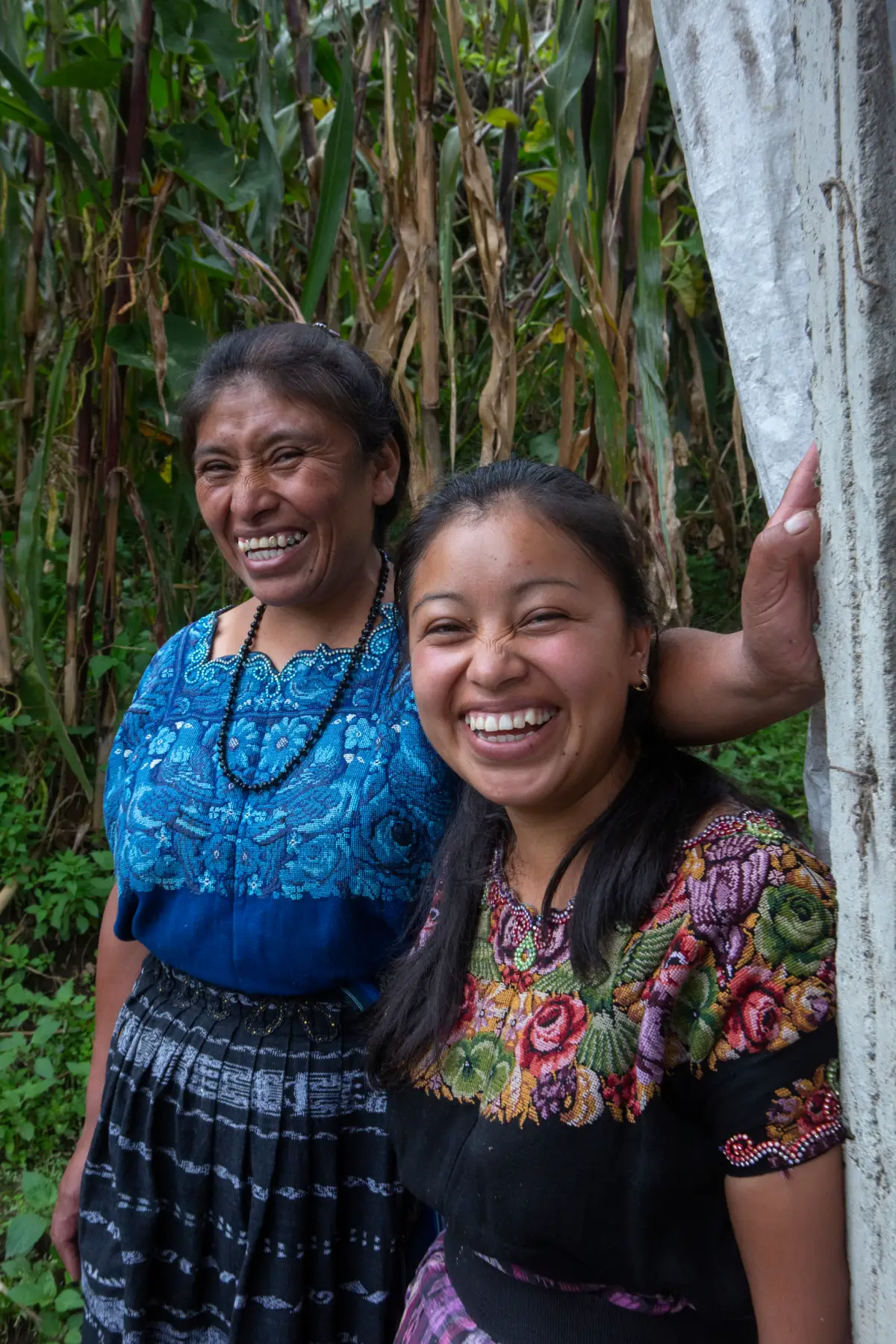 Two women smiling with trees in the background.