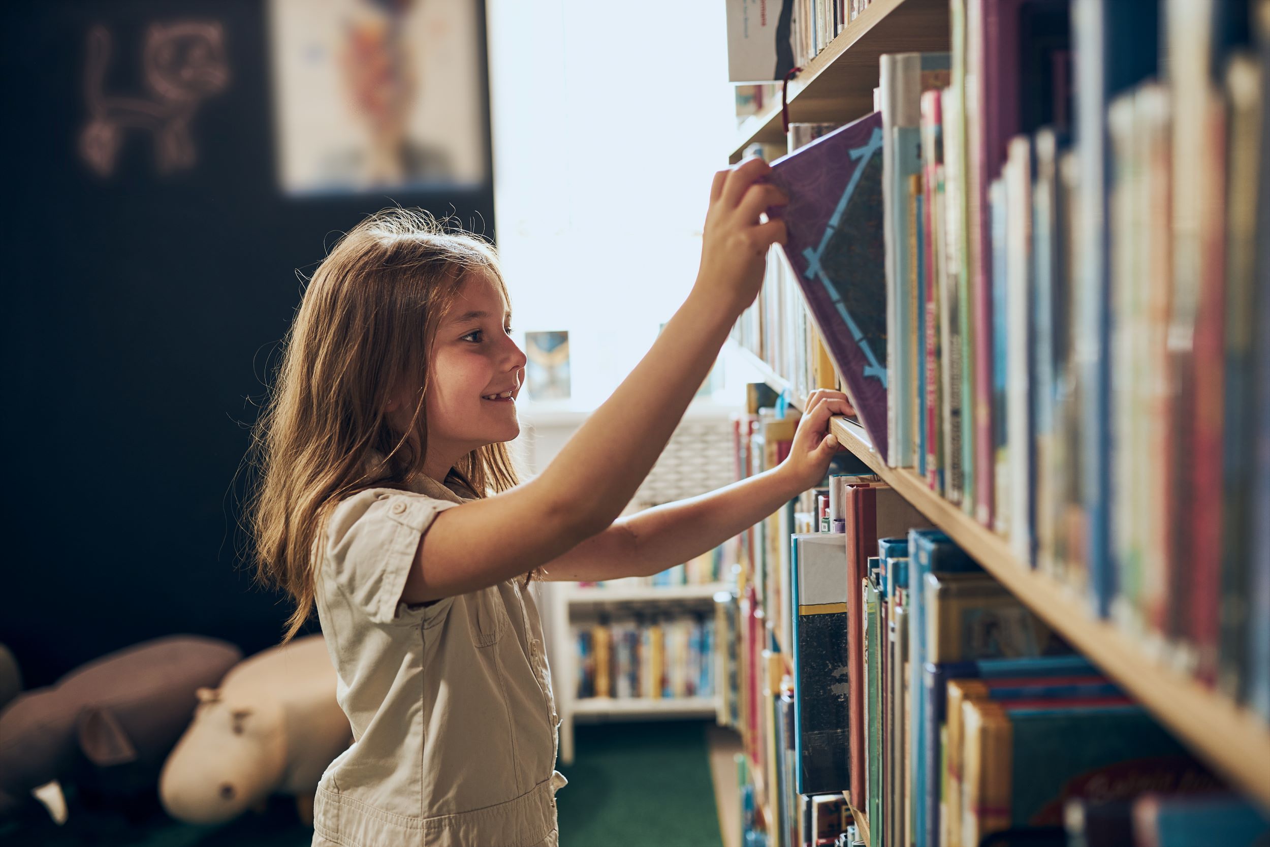 A girl picks out a book at the library.