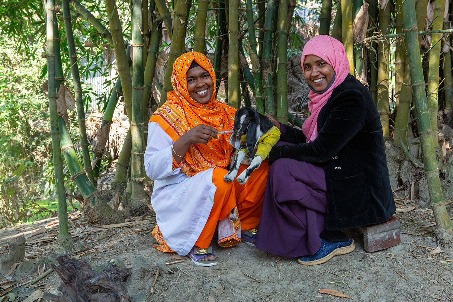 Two smiling women with a goat