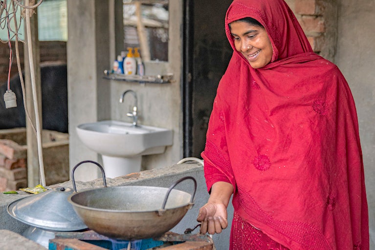 A woman in a red garment operates a biogas stove.