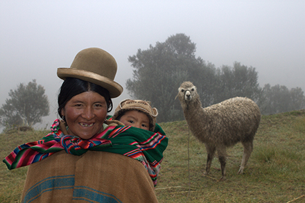 caption Mother and child pose while menacing llama lurks in the background.