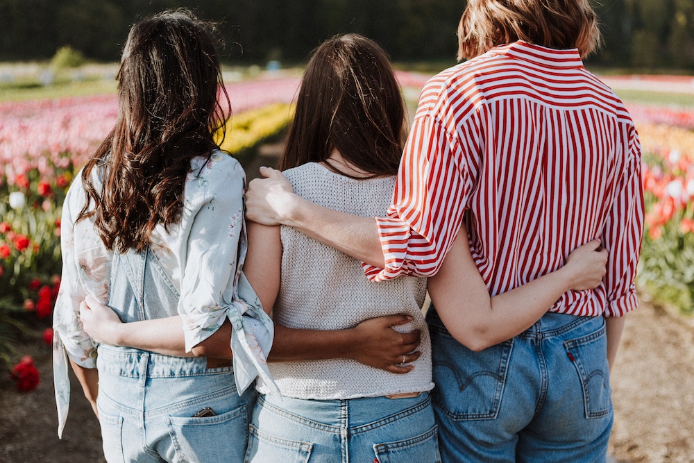 The Ring Theory can help you know best how to support loved ones. Three women with their arms around each other's backs.