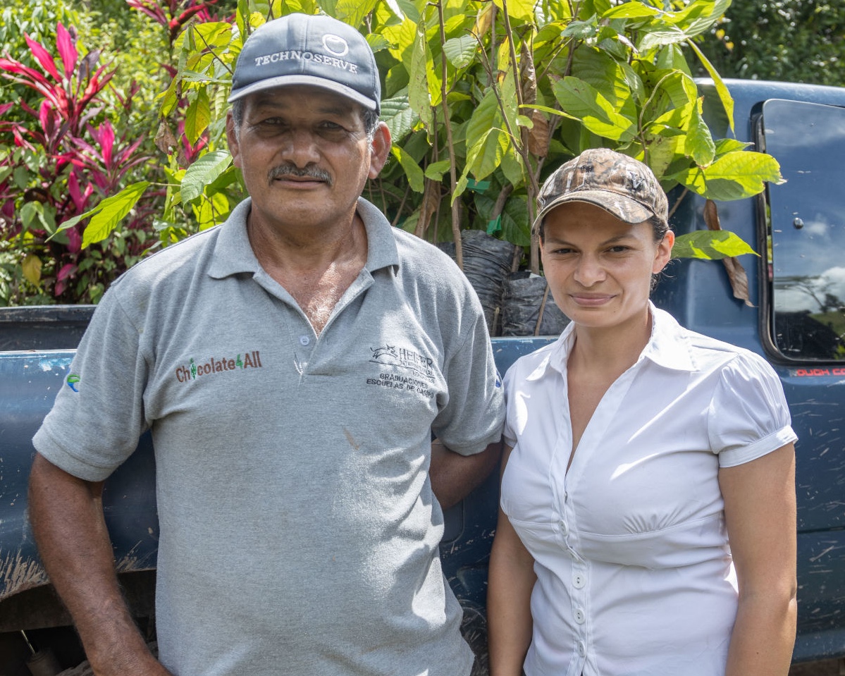 Neydi Guzmán and her father, Jose Guzmán, stand in front of a truck of cacao plants they grow in Honduras.