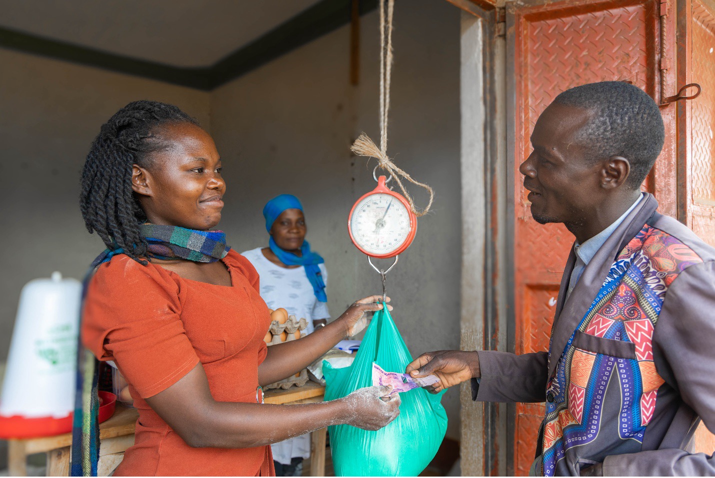Winnie Kiiza sells a bag of animal feed to a customer.